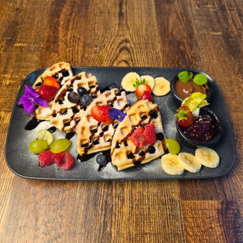 Freshly baked waffles with chocolate sauce fruit and jam