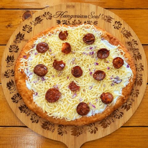 Hungarian lángos with sour cream grated cheese and smoked sausage